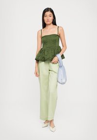 Green peplum top with textured fabric, paired with light green wide-leg pants. Accessories include a soft, light blue bag and cream shoes.