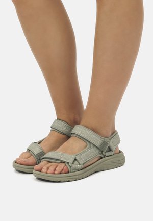 Sandalias verde claro con correas ajustables, acentos texturizados y una suela curvada para mayor comodidad. Diseño de punta abierta con detalles de hebilla visibles.