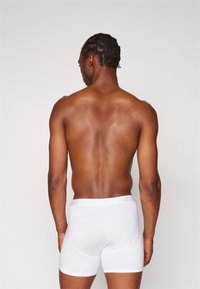 Boxer shorts en coton blanc avec une ceinture élastique douce, arborant un discret logo "GAP" gris, vus de l'arrière.