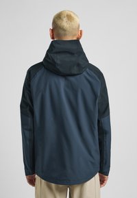 Vandafvisende jakke med en mørk marineblå krop, sorte detaljer, en justerbar hætte og lange ærmer. Glat tekstur, minimalistisk design.