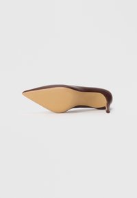 Talons hauts en cuir marron à bout pointu avec un talon aiguille élancé et une semelle jaune lisse. Caractéristiques d'un design élégant et épuré.