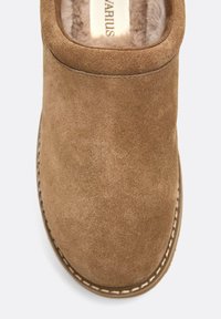 Scarpa slip-on in suede marrone con punta arrotondata, morbida fodera in pelliccia e cuciture bianche a contrasto lungo la suola. Texture complessiva liscia.