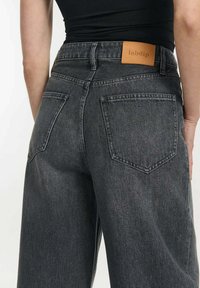 Zwarte denim jeans met een ontspannen pasvorm, voorzien van twee achterzakken en een lederen label op de tailleband. Zachte textuur met een lichte slijtaging.