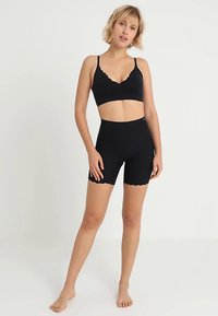 Σετ από μαύρο σουτιέν και σορτς με κυματιστά τελειώματα. Μαλακό ύφασμα, εφαρμοστό σχέδιο, μινιμαλιστικό στυλ χωρίς σχέδια ή ορατή σήμανση.