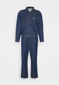 Combinaison en denim bleu foncé à manches longues, boutons sur le devant, deux poches poitrine et coupe droite aux jambes. Sans motifs ni accents visibles.