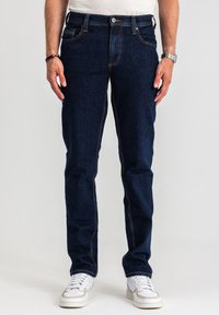 Ciemnoniebieskie dżinsy o prostym kroju, z kontrastowymi przeszyciami, pięcioma kieszeniami oraz klasycznym zapięciem na guzik i suwak.