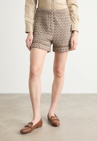 Brown and cream textured woven shorts with a subtle check pattern, featuring a waistband and rolled hem; paired with brown loafers.