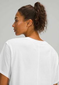 Witte katoenen t-shirt met korte mouwen, relaxte pasvorm, met een naaddetail aan de achterkant. Glad textuur en eenvoudig ontwerp.