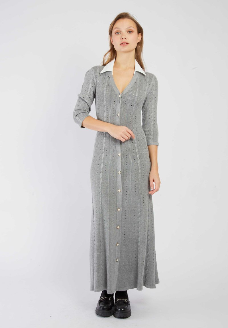 Robes maxi tricotées grises avec un décolleté en V, col blanc, manches trois-quarts, fermeture à boutons et motif texturé. Assortie avec des chaussures noires à semelles épaisses.