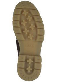 Braune Gummisohle mit diagonalen und horizontalen Rillen, strukturierten Laschen und einer cremefarbenen Zwischensohle mit Kreuzmustern.