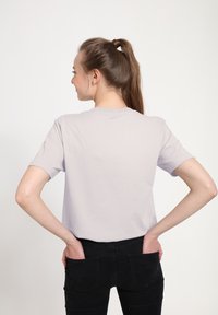Světle fialové tričko s krátkým rukávem a kulatým výstřihem. Hladká tkanina, volný střih, kombinujte s černými džínami, ruce v kapsách.