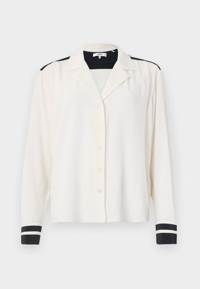 Camicia a maniche lunghe in tessuto crema con colletto, caratterizzata da accenti a righe nere sulle spalle e polsini a righe nere. Chiusura con cinque bottoni.