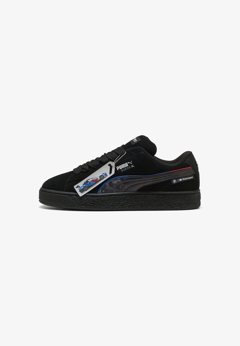 Black suede sneaker with textured sole, featuring blue and red accents, Puma branding, and a graphic tag with a car design.