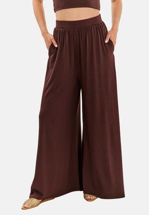Brązowe spodnie szerokie wykonane z miękkiego materiału, z elastycznym paskiem w talii i kieszeniami bocznymi, o zwiewnym kroju dla maksymalnego komfortu.