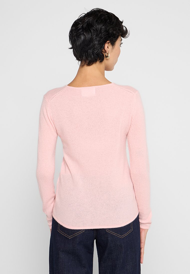 Jasnoróżowy sweter z dzianiny, z długimi rękawami, o miękkiej fakturze i okrągłym dekolcie, z detalem yoke z tyłu oraz delikatnie zaokrąglonym hemem.