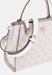 Sac à main blanc designer en matériau texturé avec une finition gris clair à motifs, quincaillerie dorée et une bandoulière amovible.