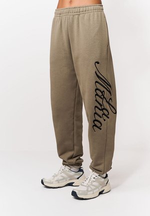 Olivovo zelené tepláky s elastickým pásom; na ľavej nohe je čierny kurzívny nápis "Maria"; vyrobené z mäkkej tkaniny.