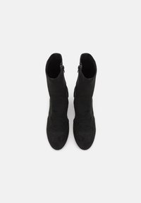 Bottines en suède noir, présentant un design élégant et lisse avec un bout arrondi et une fermeture éclair sur le côté pour un enfilage facile. Fini texturé sur l'ensemble.