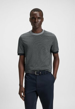 T-shirt grigio a maniche corte con tessuto testurizzato, collo rotondo a contrasto e polsini neri solidi, abbinato a pantaloni blu scuro.