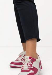 Vita och rosa sneakers med nät- och läderelement, med vita snören, rund tå och en texturerad sula. Mörk denim capribyxor.