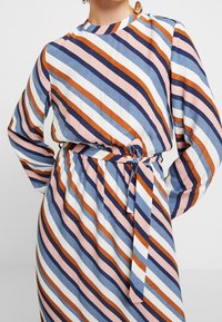 Gestreiftes Kleid mit hohem Ausschnitt und langen Ärmeln. Die Farben umfassen Rosa, Blau, Weiß und Dunkelviolett mit einer taillierten Taille und einem Gürtel.