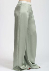 Pantaloni a gamba larga verde chiaro realizzati in tessuto liscio con una finitura satinata, caratterizzati da delicate cuciture laterali e una cintura ampia.