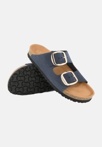 Sandali in suede blu navy con due cinturini regolabili, fibbie dorate, suola in sughero e suola in gomma testurizzata per una maggiore aderenza.