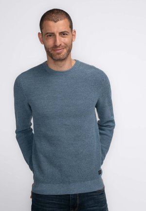 Blue knitted sweater with long sleeves, round neck, and textured fabric. Features ribbed cuffs and hem, shorter length, and brand tag at the bottom.