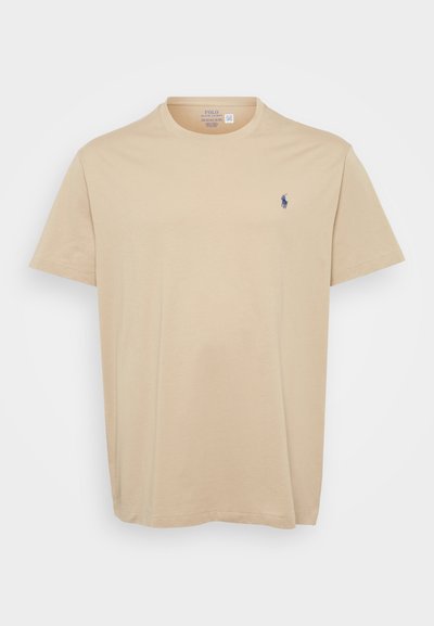 Beige színű pamut póló kerek nyakkal, rövid ujjú, a bal mellen egy kis kék hímzett logóval. Puha tapintású, laza fazonú.