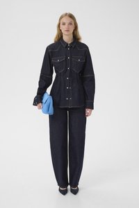 Denimskjorte med to forlommer, mørkeblå farve og synlige syninger. Kombineret med vidbenede mørke denimbukser og en blå pelsclutch.