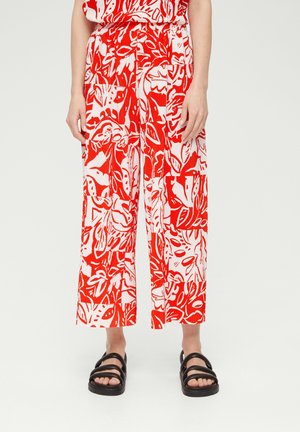 Pantaloni a gamba larga con motivo floreale rosso e bianco e una texture plissettata. Indossati con sandali neri con cinturini.