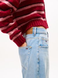 Red and pink striped knit sweater with ribbed cuffs, paired with light blue denim jeans featuring a branded leather tag and visible pockets.