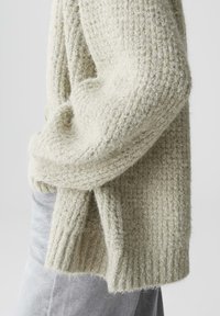 Lichtgroene, gestructureerde gebreide cardigan met een losse pasvorm, geribbelde manchetten en afgezakte schouders, met een zachte, vlezige uitstraling.