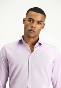 Camisa de botones de color lila claro con un cuello clásico, textura suave y un diseño ajustado. Presenta botones blancos en la parte delantera.