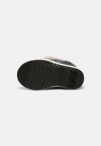 Sola de sneaker em borracha preta com padrão de ranhuras em zigzag, apresentando um forro de pelúcia cinza e material superior azul.