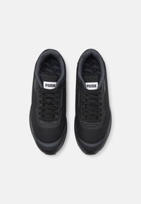 Schwarze Sportschuhe mit einem Mesh-Obermaterial, ausgestattet mit einem gepolsterten Kragen, rundem Zehenbereich und flachen Schnürsenkeln. Logo sichtbar auf der Zunge und der Innensohle.