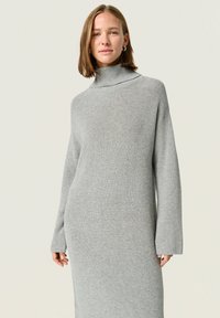 Abito a maglione grigio con scollo a dolcevita, caratterizzato da una texture a coste, maniche lunghe e una vestibilità rilassata, che arriva a metà polpaccio.
