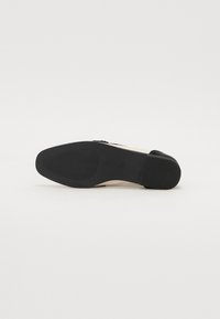 Boty s černou podrážkou a béžovým svrškem. Mají kulatou špičku, nízký podpatek a texturovanou podrážku pro lepší přilnavost. Minimalistický design, bez viditelného kování.