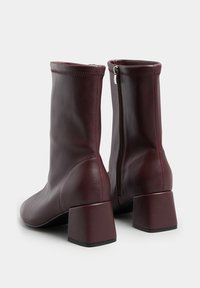 Burgundzkie botki za kostkę wykonane z gładkiej skóry syntetycznej, z blokowym obcasem, zapięciem na zamek błyskawiczny i okrągłym czubkiem.