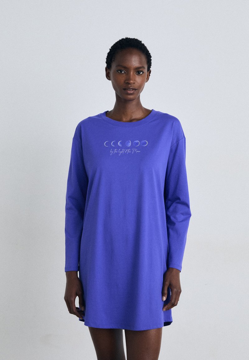 Vestido longo roxo de mangas compridas com um decote arredondado e uma ilustração das fases da lua com texto abaixo. Material de algodão suave, ajuste descontraído.