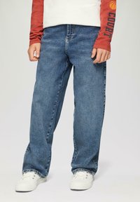 Pantalones vaqueros de mezclilla azul con corte recto, que presentan un diseño clásico de cinco bolsillos, combinados con zapatillas blancas.
