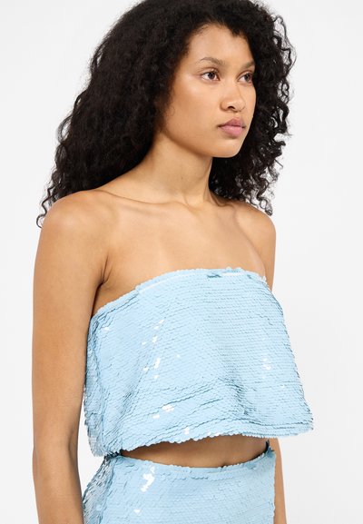 Lichtblauw met pailletten bedekte crop top met een rechte, strapless snit. Gemaakt van glanzende, overlappende cirkelvormige pailletten en een gekartelde zoom.