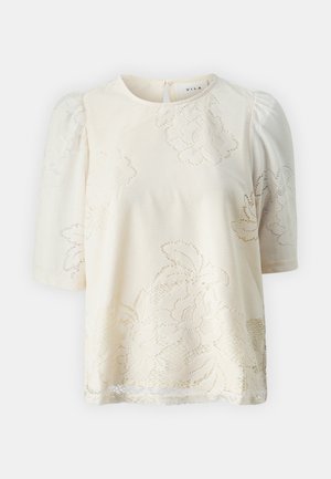 Kratka bluzica s kratkimi rokavi iz kremaste tkanine, okrašena z čipkastim cvetličnim vzorcem, okroglo izrezana, s subtilno teksturo in nabranimi pufastimi rokavi. Zapiranje na hrbtni strani s ključavnico.