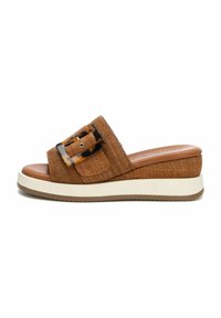 Sandalo slide intrecciato marrone con una larga fascia, caratterizzato da una grande fibbia in tartaruga. Suola platform con una linea bianca e fondo marrone texturizzato.