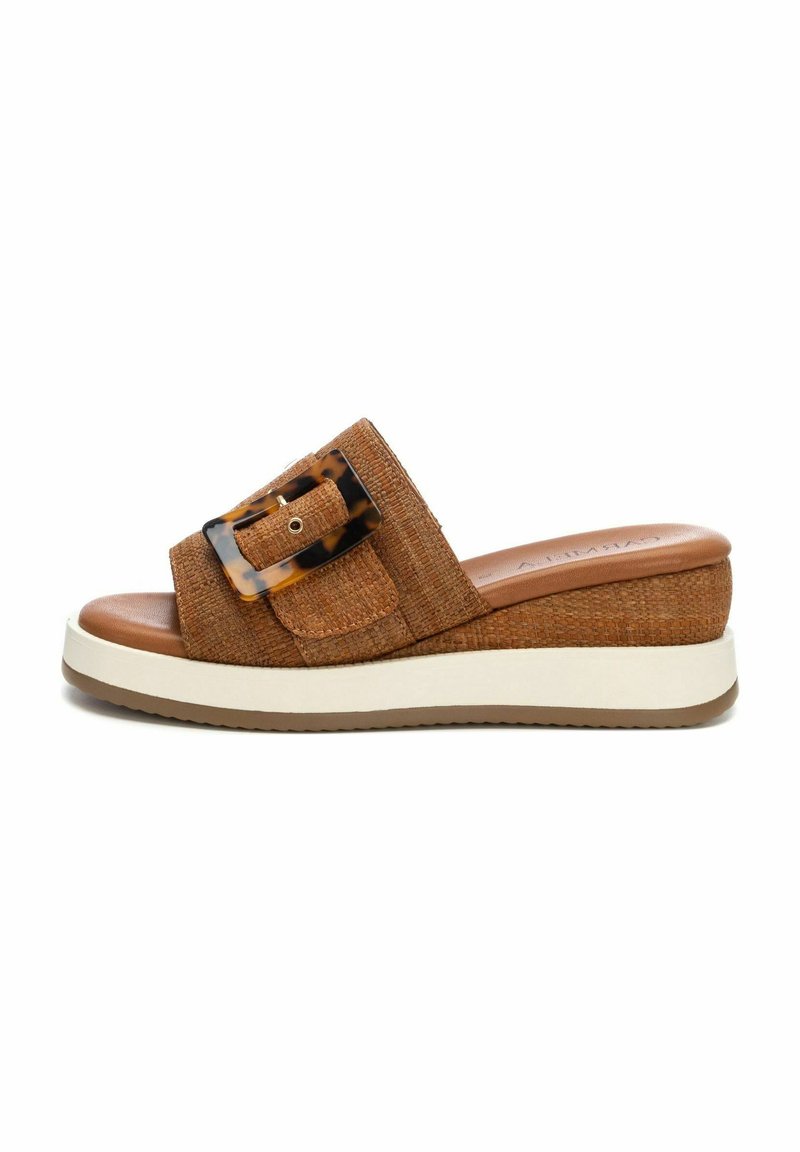 Sandalo slide intrecciato marrone con una larga fascia, caratterizzato da una grande fibbia in tartaruga. Suola platform con una linea bianca e fondo marrone texturizzato.