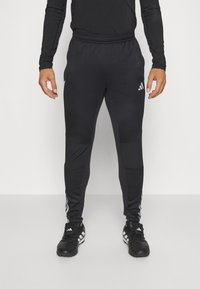 Schwarze Sporthose aus dehnbarem Material, mit schmal zulaufendem Schnitt, elastischem Bund und seitlichen Streifen mit Logo-Akzenten.