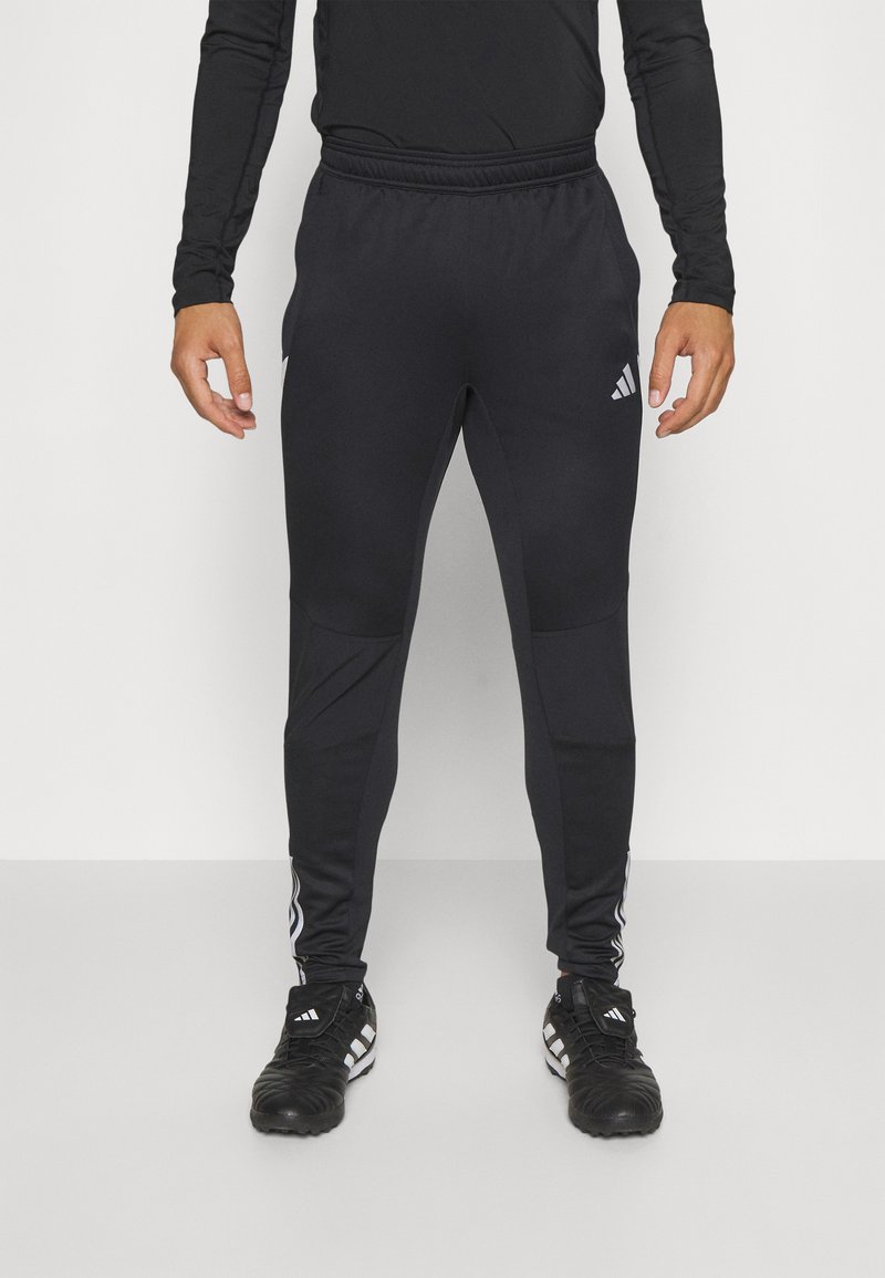 Schwarze Sporthose aus dehnbarem Material, mit schmal zulaufendem Schnitt, elastischem Bund und seitlichen Streifen mit Logo-Akzenten.