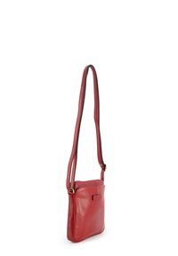 Small red leather crossbody bag with long adjustable strap and subtle logo patch on front, shown against white background.