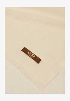 Cremefarbenes Gewebe mit einem braunen "GOBI Organic"-Etikett und Fransen an den Rändern.