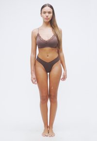 Καφέ σετ εσωρούχων με δαντελένιες λεπτομέρειες. Το σουτιέν έχει λεπτές τιράντες και μαλακό κύπελλο· το ταίριασμα είναι ψηλόμεσο σλιπ. Ομαλή υφή.